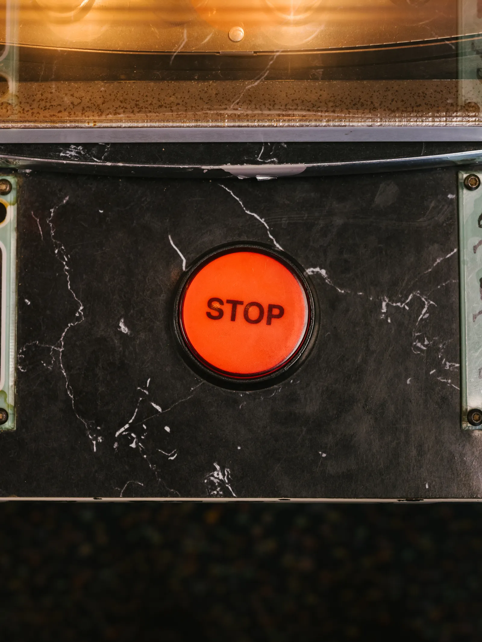 A glowing red STOP button set in a black marble panel.