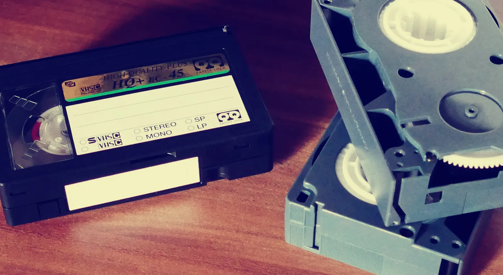 Three VHS cassettes on a wooden table.