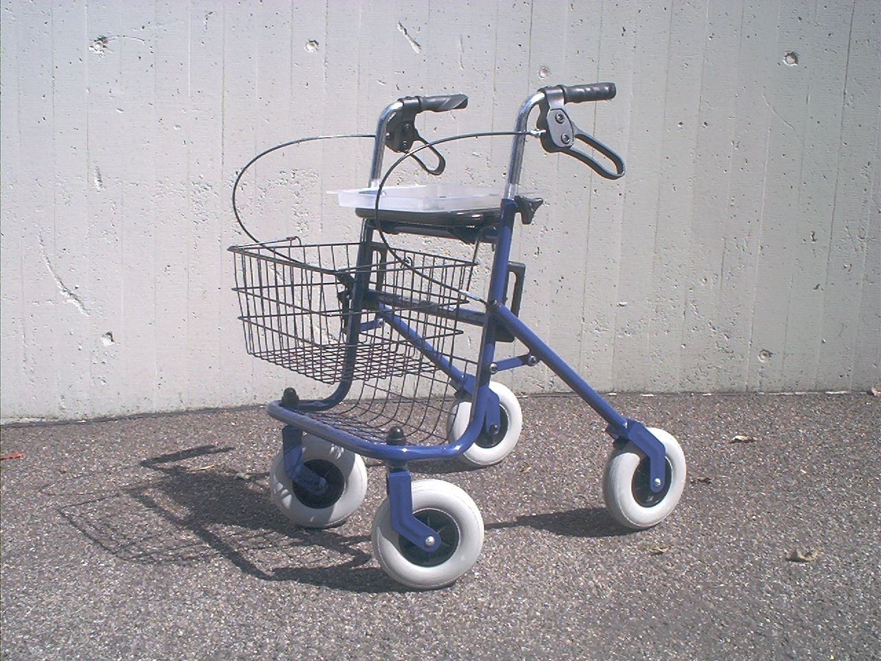 An empty blue rollator walker with a basket.